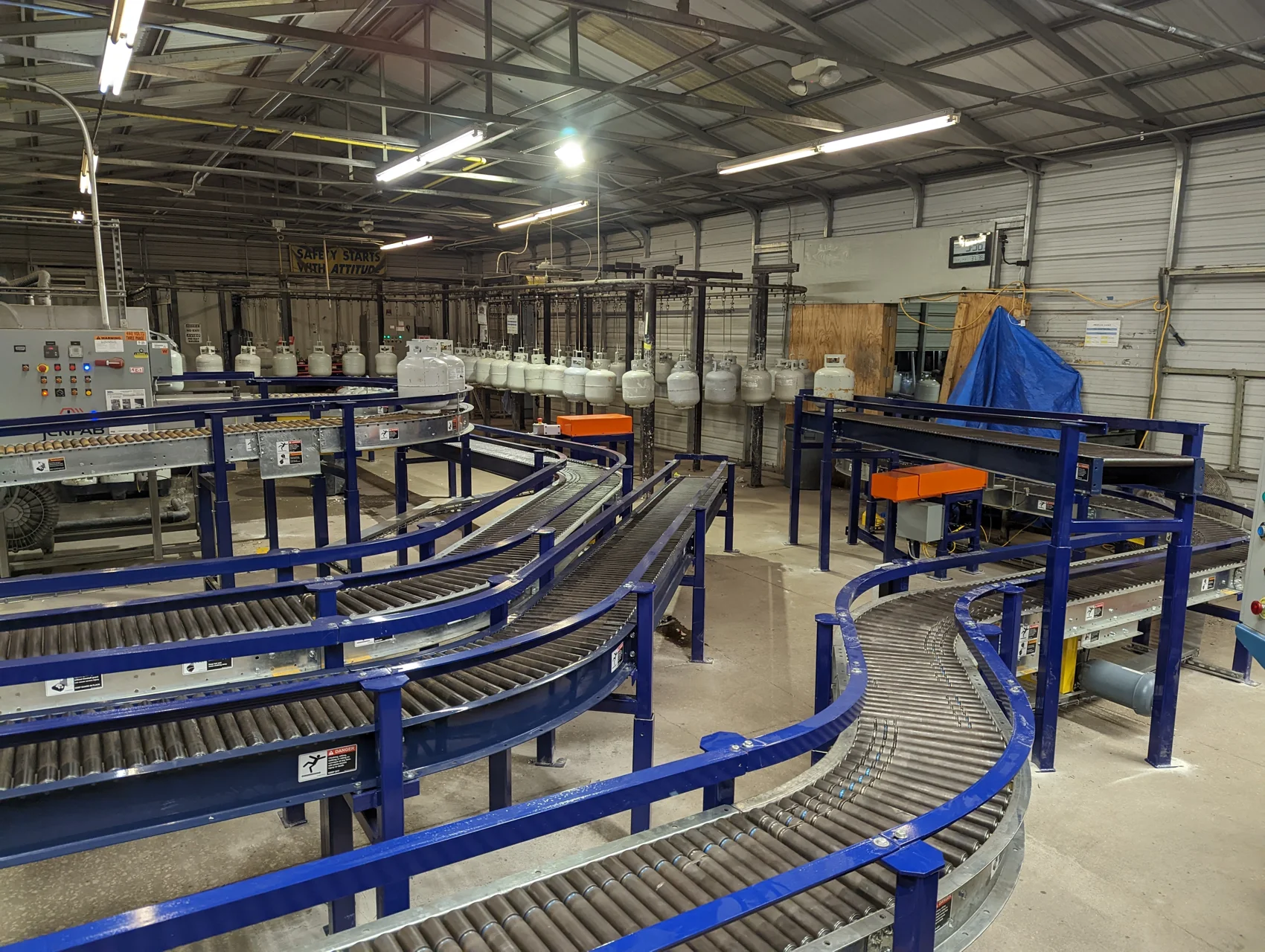Industrial conveyor systems with blue guardrails feeding an overhead conveyor line at Blue Rhino
