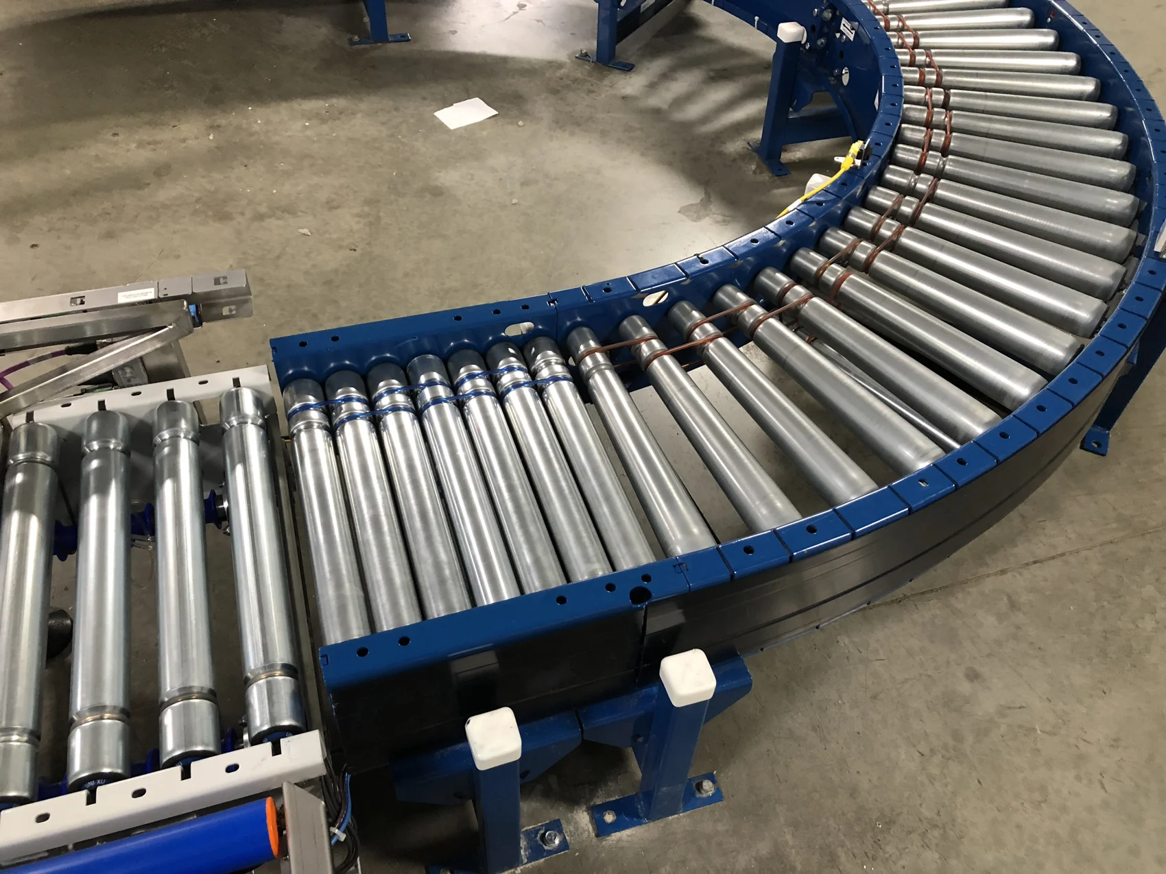 Powered roller conveyor curve with blue side frames on a plant floor