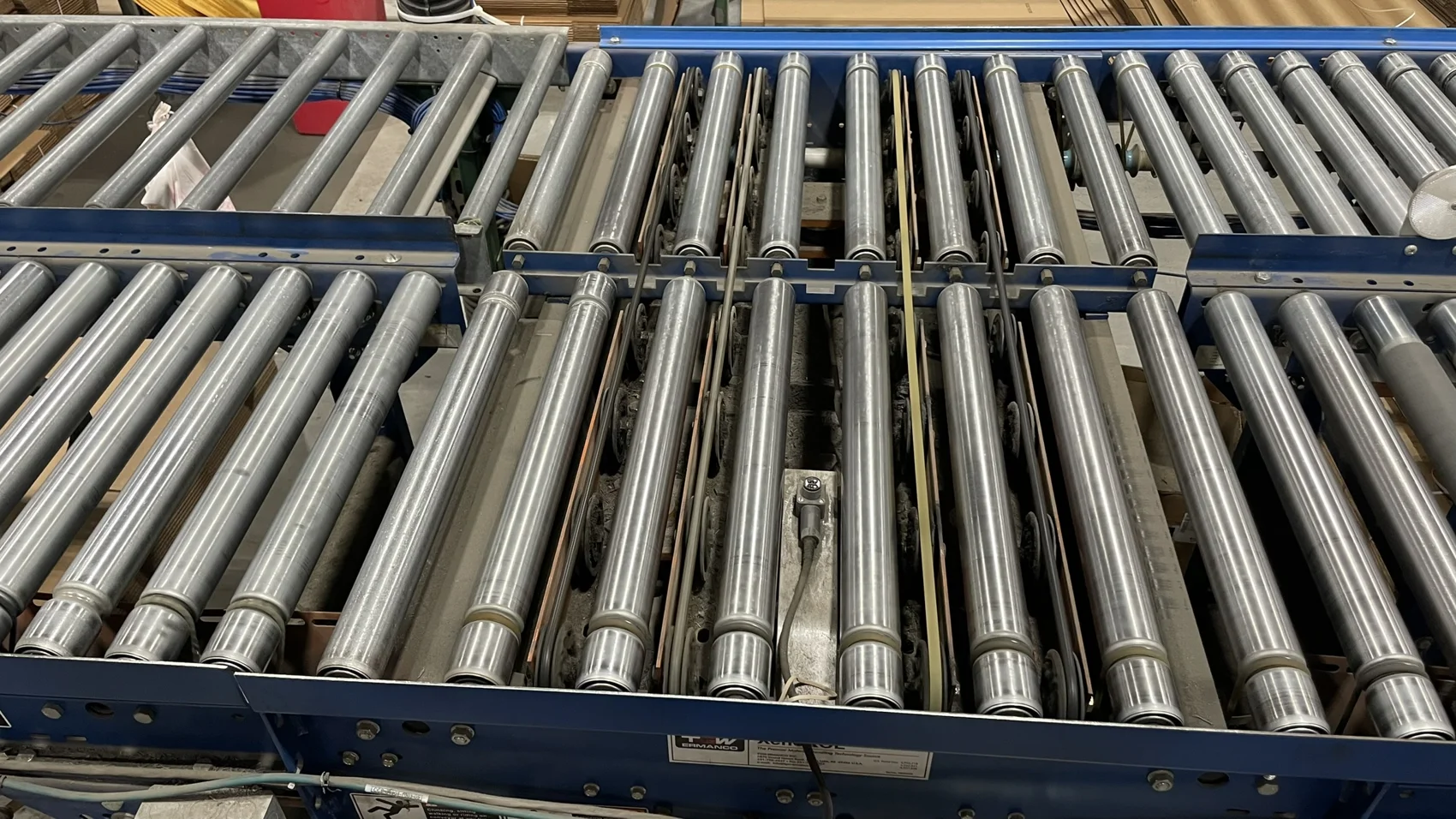 Right-angle transfer section on a roller conveyor, with lift belts running between the rollers